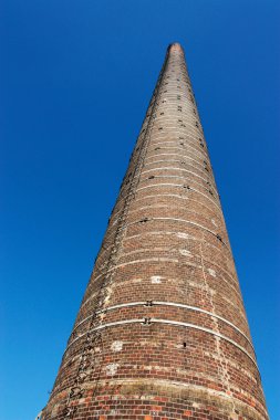 Industrial tall brick chimney against blue sky clipart