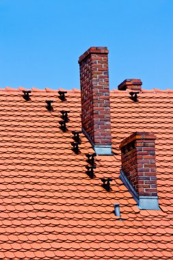 Red tiles roof and bricks chimney on blue sky clipart