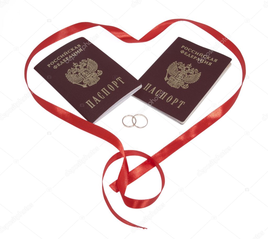 Two passports, two golden rings in red heart, isolated.