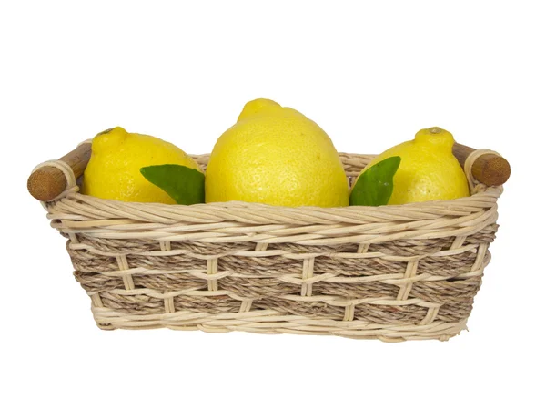 Three yellow lemons with leaves in a wattled basket. — Stock Photo, Image