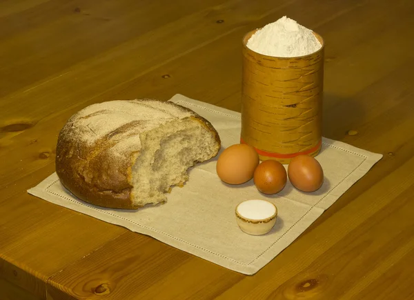 Pan de centeno, sal, harina en una caja y huevos en una servilleta de lino . — Foto de Stock