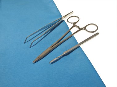 Mavi kumaş parçası üzerinde metal tıbbi aletleri.