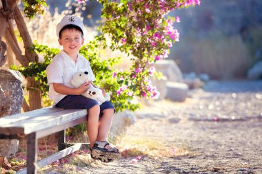 Three years old boy sitting on bench clipart