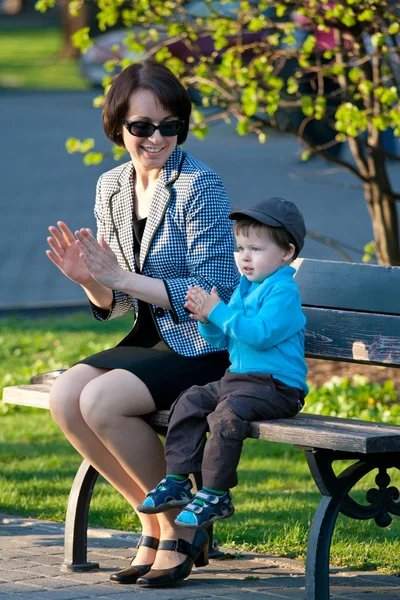 Joven madre y su hijo sentados en el banco —  Fotos de Stock