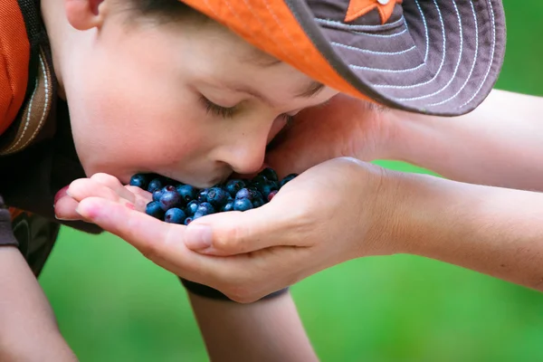 Милый мальчик ест ягоды с маминой руки. — стоковое фото