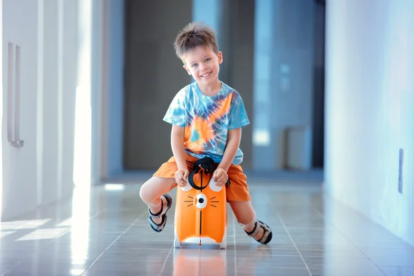 Bonito menino de três anos sentado em uma mala — Fotografia de Stock