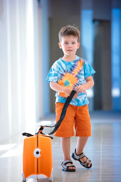 Ein süßer kleiner Junge mit orangefarbenem Koffer — Stockfoto