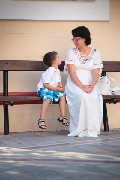 Happy mother and son sitting on bench — Stock Photo, Image