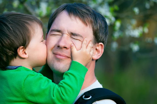 Маленький сын целует своего отца на улице — стоковое фото