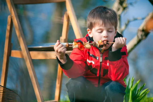 Liten pojke med glädje äter grillade grönsaker — Stockfoto