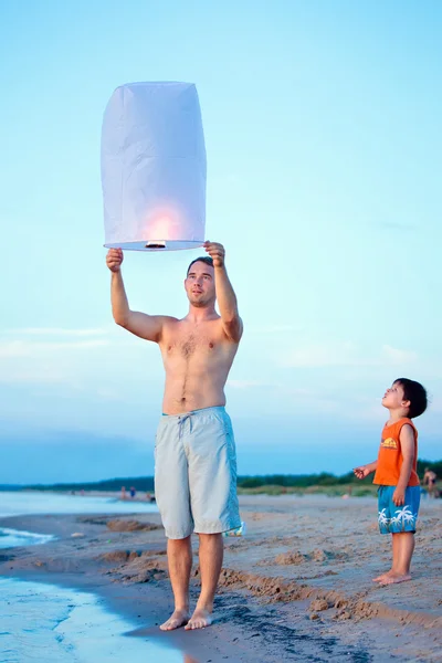 Счастливые папа и сын летят огненный фонарь вместе — стоковое фото