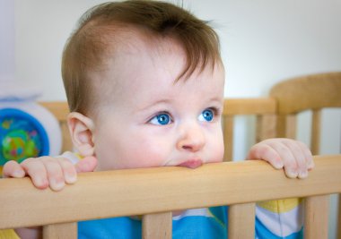 Baby Boy chomps his wooden bed clipart