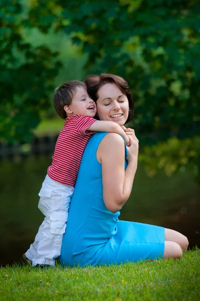 Due anni ragazzo abbraccia la sua giovane mamma nel parco — Foto Stock