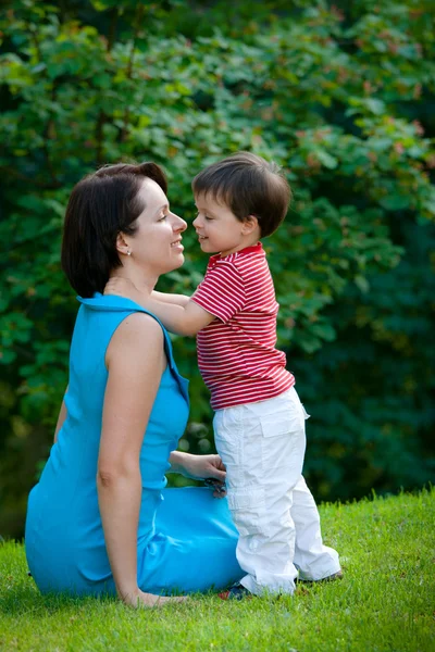 Двухлетний мальчик обнимает свою молодую маму в парке — стоковое фото