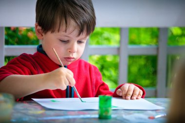 Cute little boy painting with brush clipart