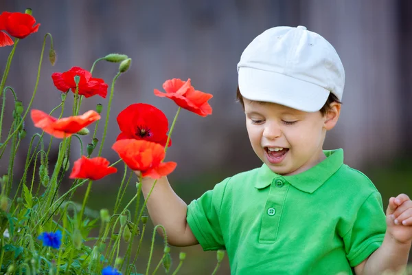 Bonito menino brinca com uma flor selvagem — Fotografia de Stock