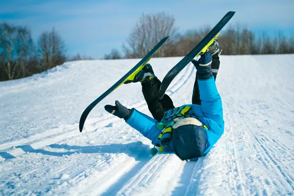 Young boy with cross-country skis lying on snow — Stock Photo, Image