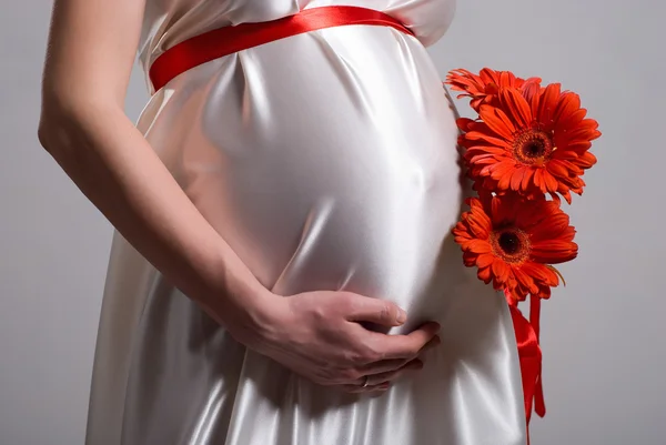 Mujer embarazada sosteniendo su vientre y flor —  Fotos de Stock