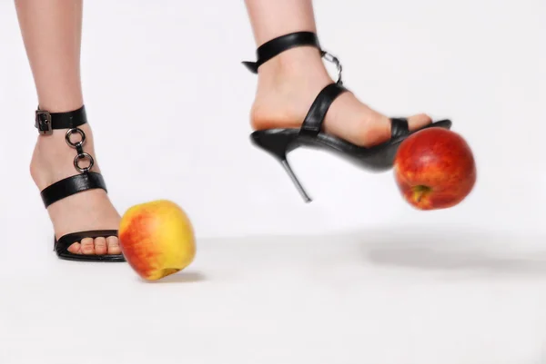 Ноги в сандалиях пинают яблоко — стоковое фото