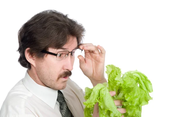 Человек с удивлением смотрит на лист салата — стоковое фото