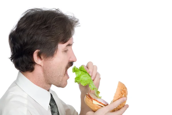 Muž dostane od hamburger list salátu a jí — Stock fotografie