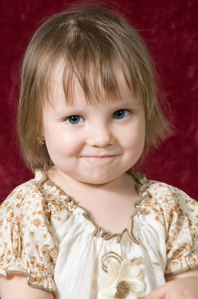 Porträtt av den fina lilla flickan på en röd bakgrund — Stockfoto