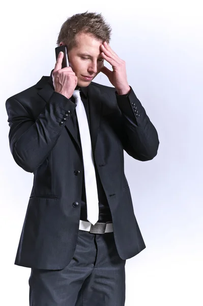 Деловой человек в черном костюме и мобильный телефон с головной болью — стоковое фото