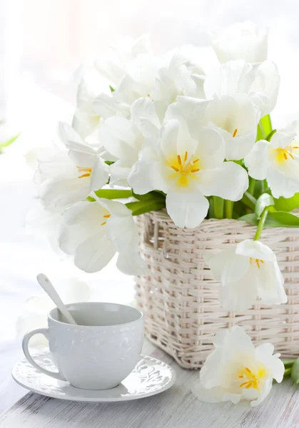 White tulips in a basket and cup of tea — Stock Photo, Image