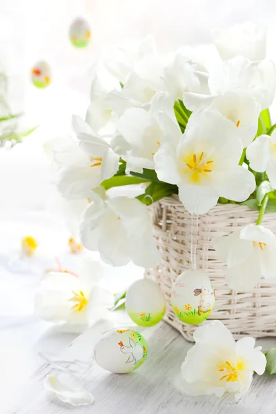 Белые тюльпаны в корзине и пасхальные яйца — стоковое фото