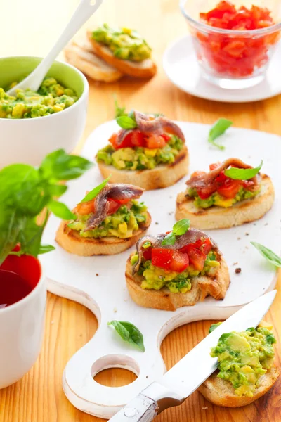 Crostini with avocado,tomato and anchovy — Stock Photo, Image