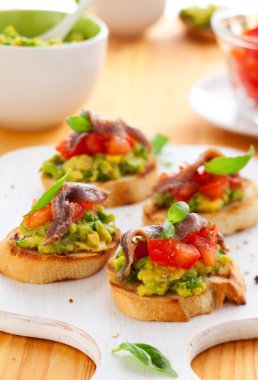 Crostini with avocado,tomato and anchovy