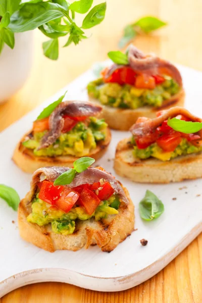 Crostini with avocado,tomato and anchovy — Stock Photo, Image