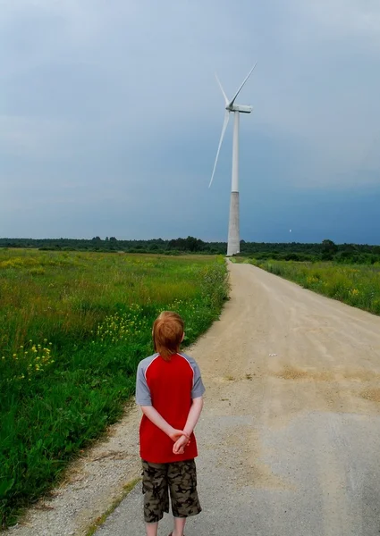 Red-head boy watching the wind-powered generator — Stock Photo, Image