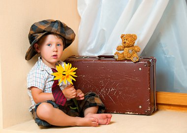 Cute little boy with the flower. He is wearing a hat. clipart