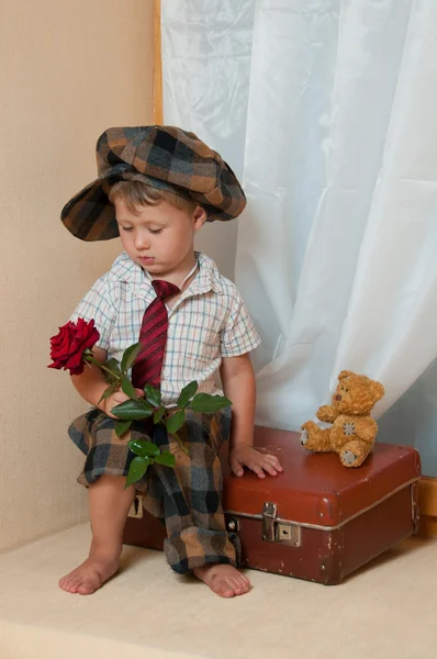 可爱的小男孩坐在一个旧的手提箱上的花。他我 — 图库照片
