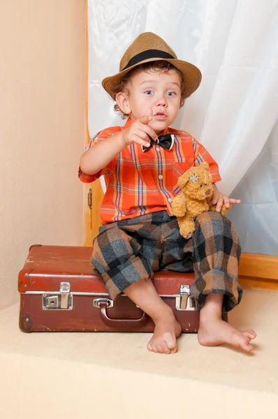 Chłopiec z misiem, siedząc na walizkę. — Zdjęcie stockowe
