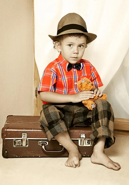 Chłopiec z misiem, siedząc na walizkę. — Zdjęcie stockowe