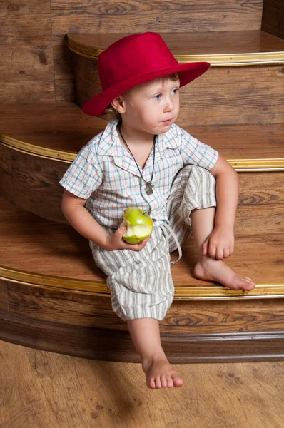 Ładny chłopak z jabłkiem w ręku, siedząc na schodach. — Zdjęcie stockowe