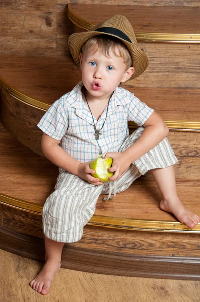 Un chico lindo con una manzana en la mano sentado en las escaleras . —  Fotos de Stock