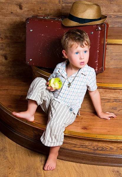 Un ragazzo carino con una mela in mano seduto sui gradini . — Foto Stock