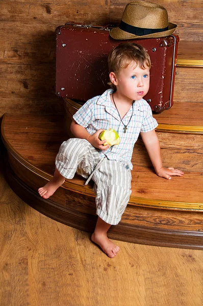 Ένα χαριτωμένο αγόρι με ένα μήλο στο χέρι του καθισμένος στα σκαλιά. — Φωτογραφία Αρχείου