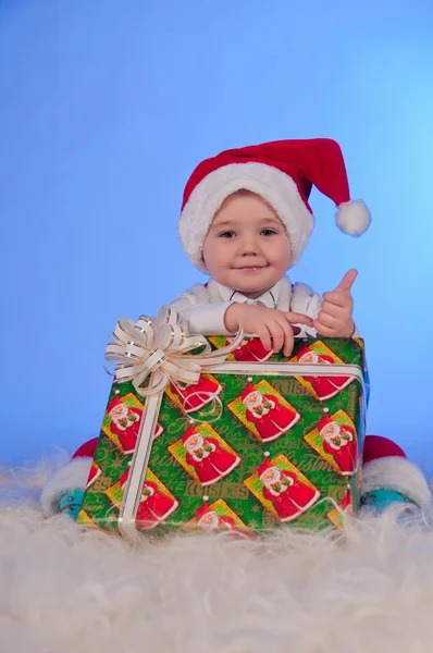 プレゼント ボックスとサンタのスーツで赤ちゃんを笑って面白い. — ストック写真