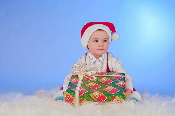 Lustiges lachendes Baby im Weihnachtsmannanzug mit Geschenkbox. — Stockfoto