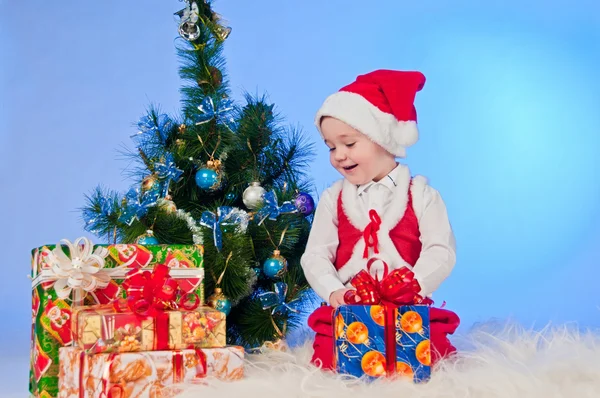 Divertente bambino ridente in costume da Babbo Natale con una scatola regalo . Immagine Stock