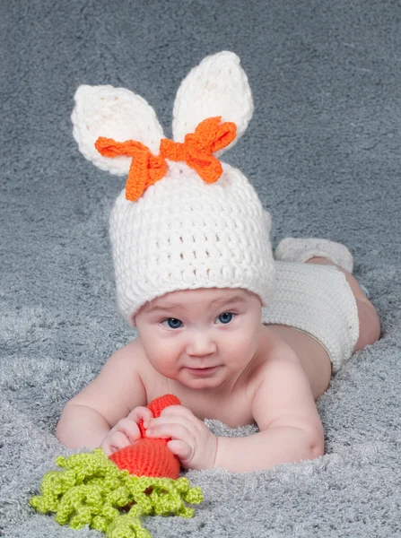 Un niño pequeño con orejas de conejo. Acostado boca abajo con una ca —  Fotos de Stock
