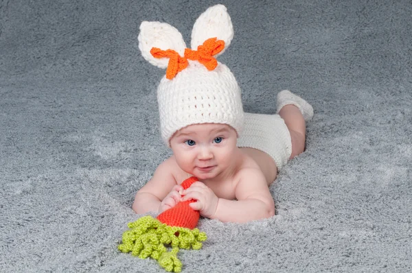 Un niño pequeño con orejas de conejo. Acostado boca abajo con una ca — Foto de Stock