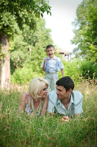 Portrait of happy family lying down on grass. — Stock Photo, Image
