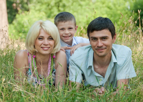 Portrait of happy family lying down on grass. — Stock Photo, Image