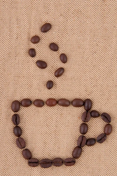 Una tazza di chicchi di caffè con fumo sullo sfondo di iuta . — Foto Stock