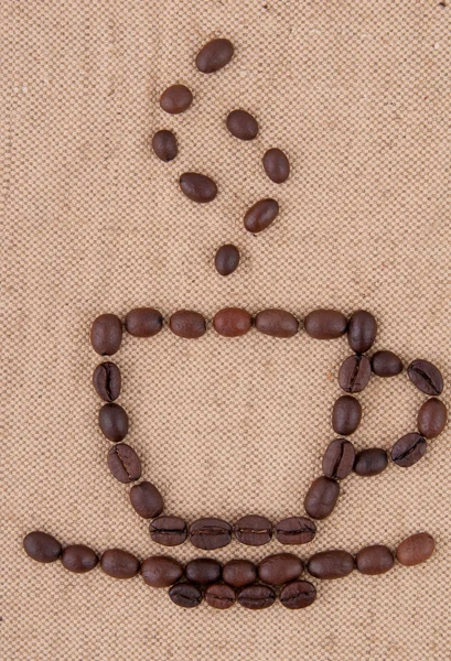 Una taza de granos de café con humo en el fondo de la arpillera . — Foto de Stock